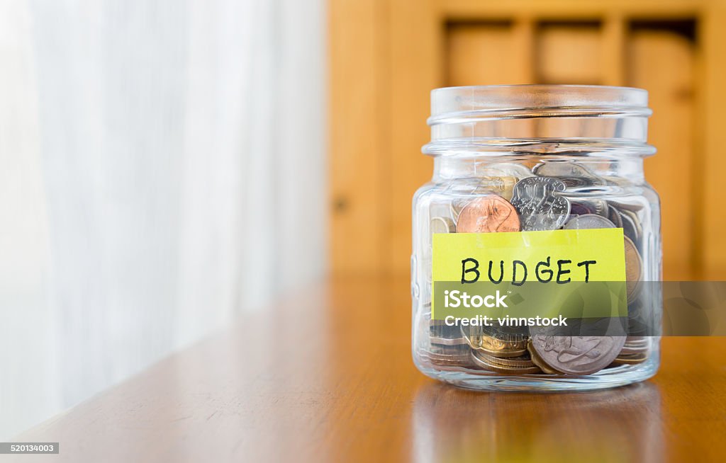 Budget planning and saving money Glass bank with many world coins and budget word or label on saving money jar Coin Stock Photo