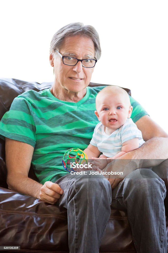 Grandfather holding his baby grandson Grandfather is holding his four month old baby grandson on his lap.  They are sitting on a chair holding a colorful toy. Studio shot using a Canon 5D mark 3 camera.  rm Males Stock Photo