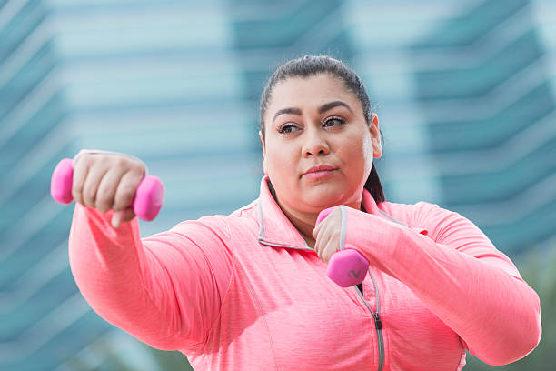istock Overweight Hispanic woman exercising with handweights 520135858