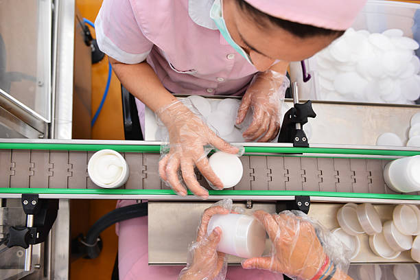 istock Female workers puts packages of cream in the machine 520162609