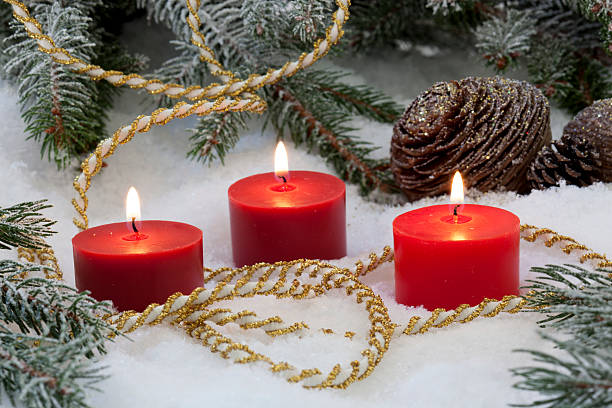 istock red candles burning for Christmas in snow and fir tree 520163167