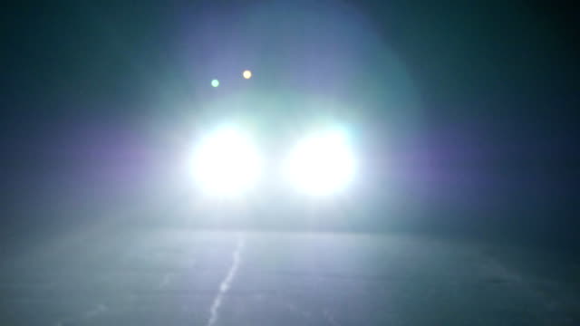 Moving car with lights at night. Car going on empty night road. In total darkness seen only the bright light of car headlights.