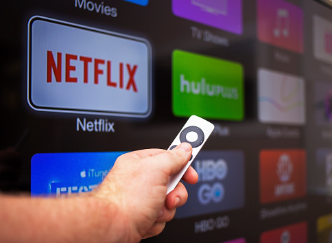 Las Vegas, USA - October 24, 2014: A man in his 30's browsing the channel selections on Apple TV at his home in Las Vegas. Apple TV is a digital media player  developed and sold by Apple Inc. It is a small network appliance and entertainment device that streams movies and television shows to a television screen.