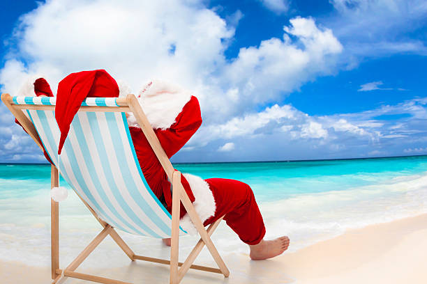 pai natal sentado em cadeiras de praia.  conceito de férias de natal. - christmas beach sun tropical climate imagens e fotografias de stock