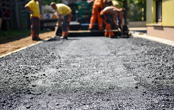Team of Workers making and constructing asphalt road constructio Team of Workers making and constructing asphalt road construction with finisher. The top layer of asphalt road on a private residence house driveway compactor photos stock pictures, royalty-free photos & images