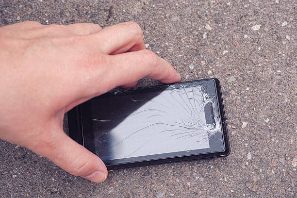 istock Person picking up a cracked smartphone 520167328