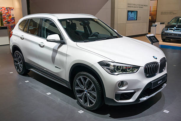 BMW X1 luxury compact SUV Brussels, Belgium - Januari 12, 2016: White BMW X1 luxury compact SUV car. The car is on display during the 2016 Brussels Motor Show. The car is displayed on a motor show stand, with lights reflecting off of the body. bmw dealership stock pictures, royalty-free photos & images