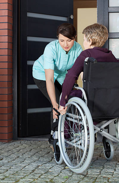 istock Caregiver helping disabled woman entering home 520169115