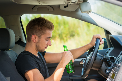 Drunk Driver Drinking Beer while Driving a Car