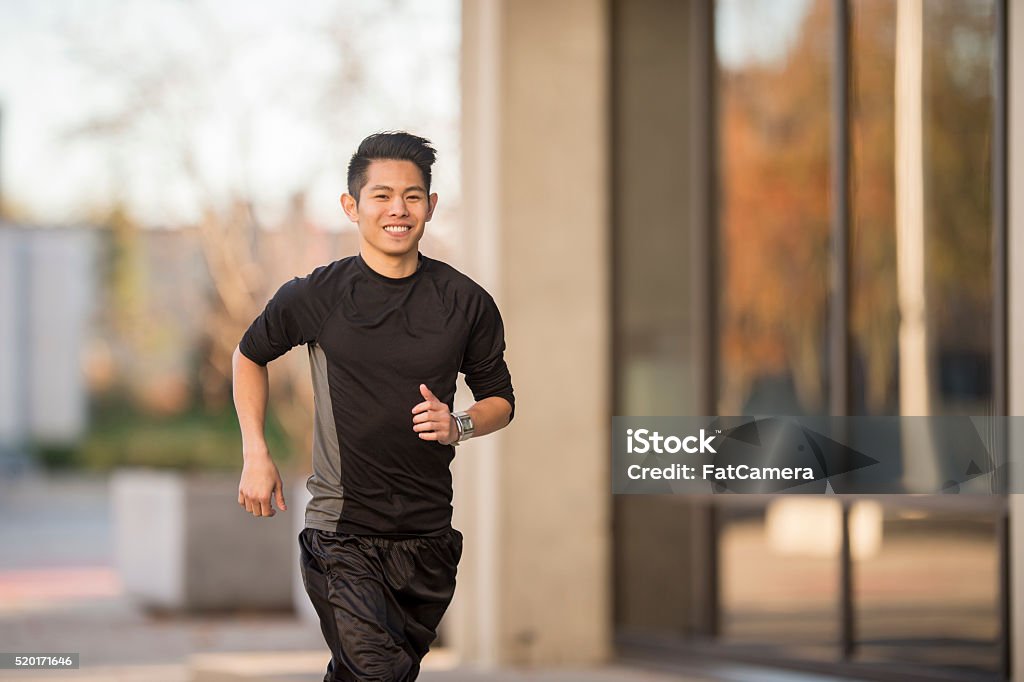 Man Exercising Outside A man is exercising and working out my jogging through the city. Asian and Indian Ethnicities Stock Photo