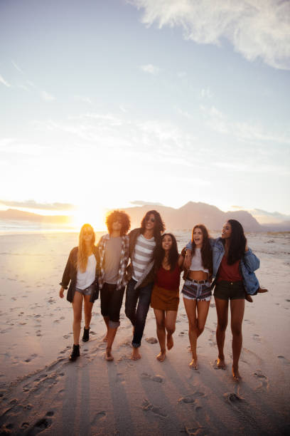 Fun loving hipster friends embracing on the beach at sunset