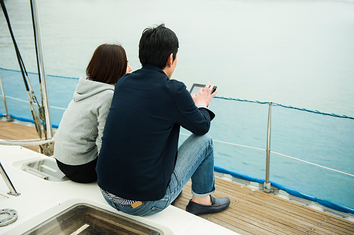 Two mature adults using a digital tablet on a yacht