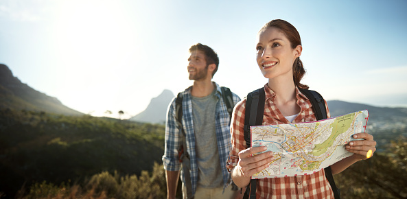 Shot of a young couple looking at a map while hiking
