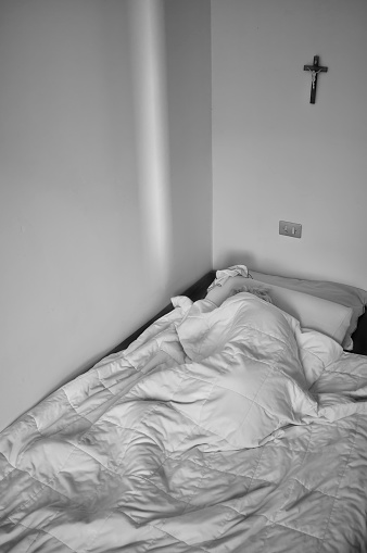 old senior woman alone, sleeping in bed under the covers