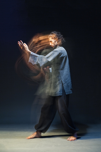 full-length portrait of man in kimono excercising Martial Arts on black bacground with multiexposition