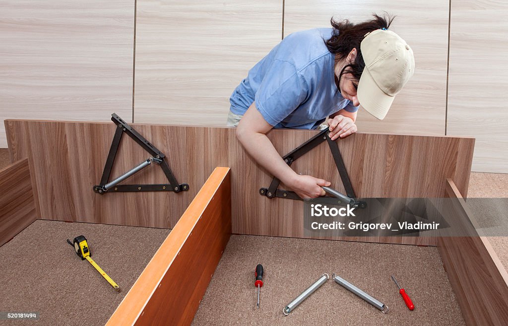 Flat Pack furniture assembly and installation service, women handyman working. Self assembling furniture at home, Women putting together self assembly furniture, assemble adjustable lift bed frame spring mechanism system. Bed Frame Stock Photo