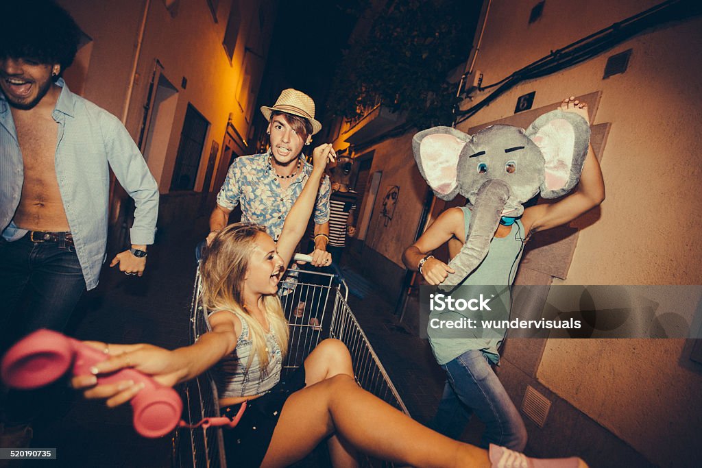 Partying Teenagers Being Silly In Street Hipster teenagers partying and being silly with shopping cart in street Party - Social Event Stock Photo