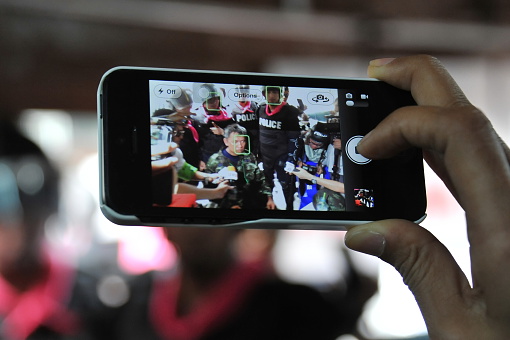 Bangkok, Thailand - August 7, 2013: A journalist uses a smartphone to capture an interview of activist leader and former army officer Songklod Chuenchupol after his arrest during an anti-amnesty bill rally near the Thai Parliament.