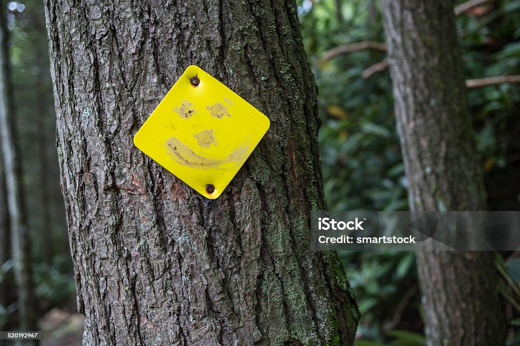 Mud used to draw smiley face on a trail marker Someone used trail mud to transform a diamond shaped trail marker into a smiley face. Anthropomorphic Smiley Face Stock Photo
