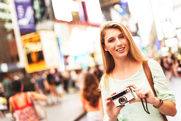 istock pretty woman smiling on times square with camera 520193289