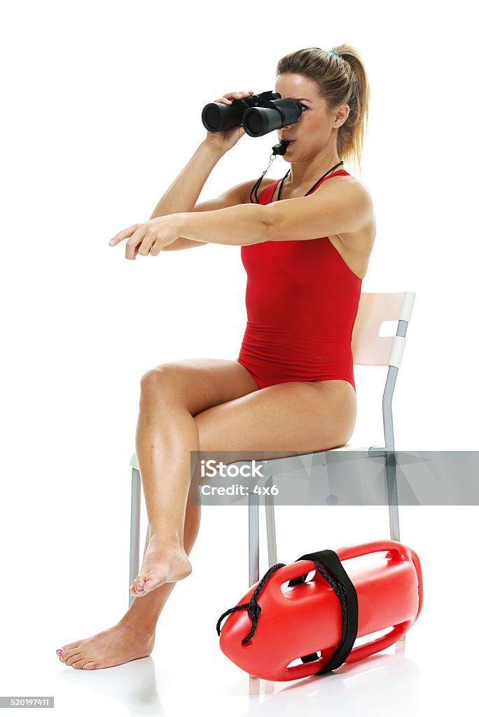 Female lifeguard searing with binoculars whistling Female lifeguard searing with binoculars whistlinghttp://www.twodozendesign.info/i/1.png Lifeguard Stock Photo