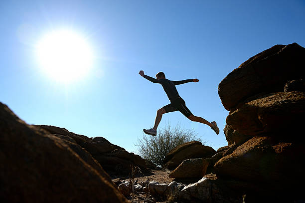 istock Silhouetted trail runner jumping from rock to rock 520197643