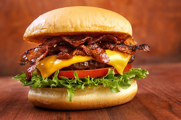 Bacon burger Bacon burger with beef patty on red wooden table cheddar cheese photos stock pictures, royalty-free photos & images