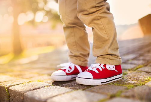 Close-up of little boy standing on tiled pavement in summer park