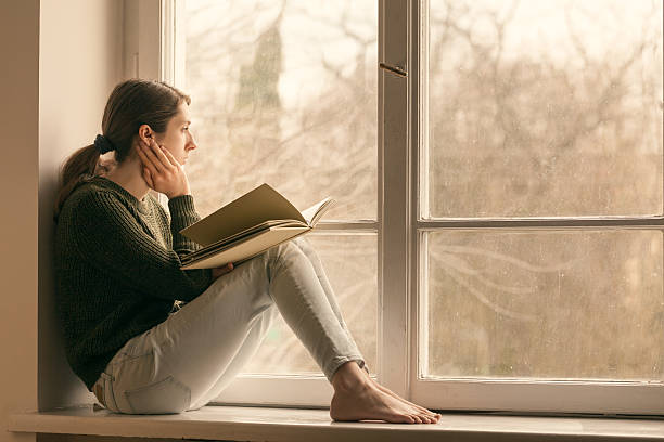 istock Woman reading a book on the window sill. 520228762