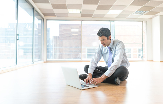 Business man at a new office working on a laptop computer sitting on the floor