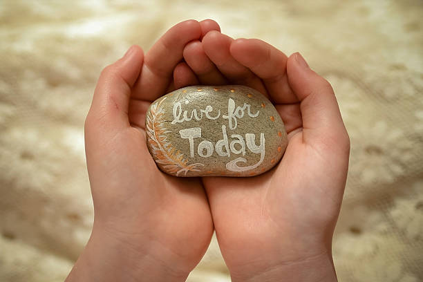 istock Live For Today painted rock in hands 520233698