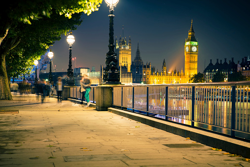 View of London England skyline including Big Ben, Westminster and blur of pedestrians seen at night.