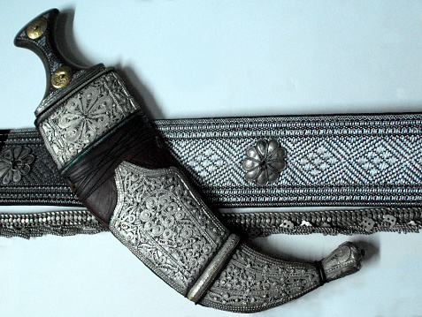 A beautiful antique sword with a bronze hilt and a leather sheath. On a dark abstract background.