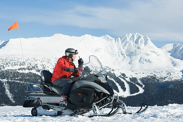 Snow patrol rescue worker sitting on snowmobile, using walkie talkie Snow patrol rescue worker sitting on snowmobile, using walkie talkie ski patrol photos stock pictures, royalty-free photos & images