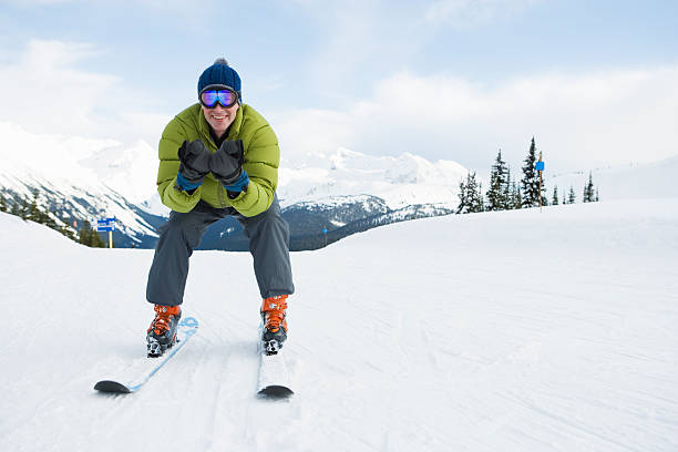 Young man skiing down ski slope and smiling, front view