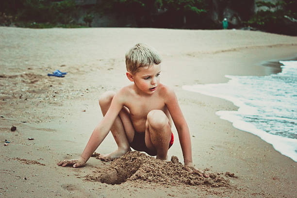 istock young boy playing in sand and waves on the beach 520262301