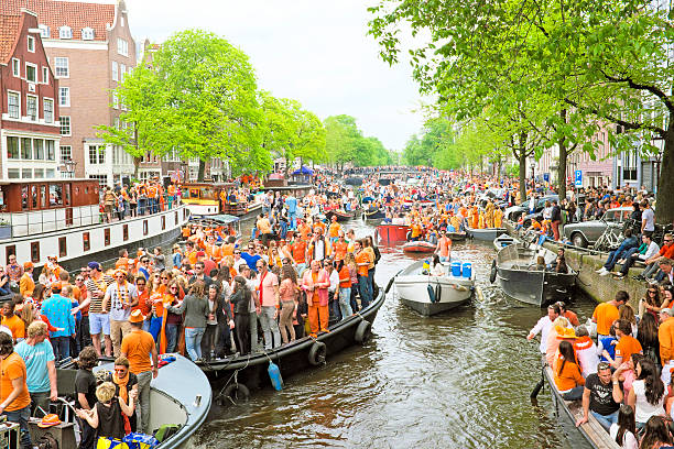 Amsterdam canals full of boats and people at kings day stock photo