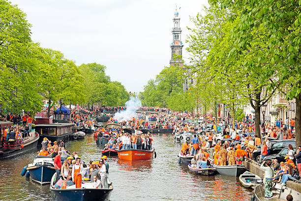Amsterdam canals full of boats and people at kings day Amsterdam The Netherlands - April 26, 2014: Amsterdam canals full of boats and people in orange at the Prinsengracht during the celebration of kings day on April 26, 2014 in Amsterdam, The Netherlands canal house photos stock pictures, royalty-free photos & images