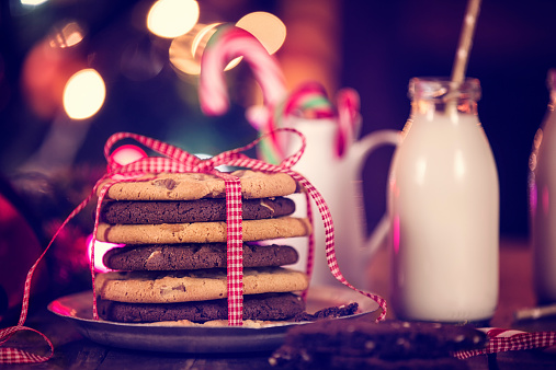 Christmas Cookies on a stack. One with wihte chocolate chips and one with brown chocolate chips and so one. The stack is tied up toghether with a ribbon.