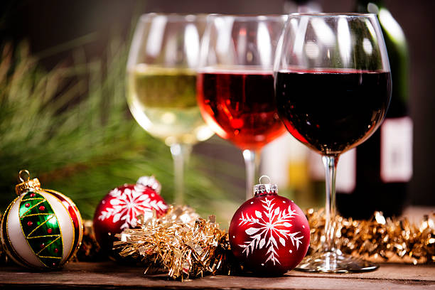 Wine, glasses on rustic outdoor dining table. Christmas ornaments. Christmas party. Wine tasting. Red, white, and rose wine selections on outdoor patio table.  Wine bottles. Rustic wooden table.  Pine twig decor to left.  Christmas ornaments, tinsel foreground.  rose wine photos stock pictures, royalty-free photos & images