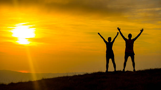 istock Couple Looking at Sunset With Their Arms Raised 520280277