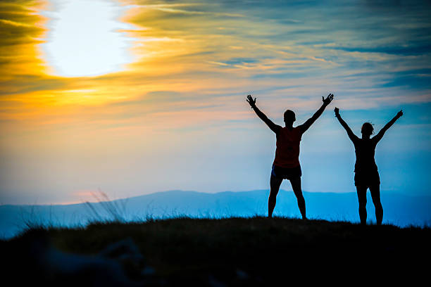 istock Couple Looking at Sunset With Their Arms Raised 520280337
