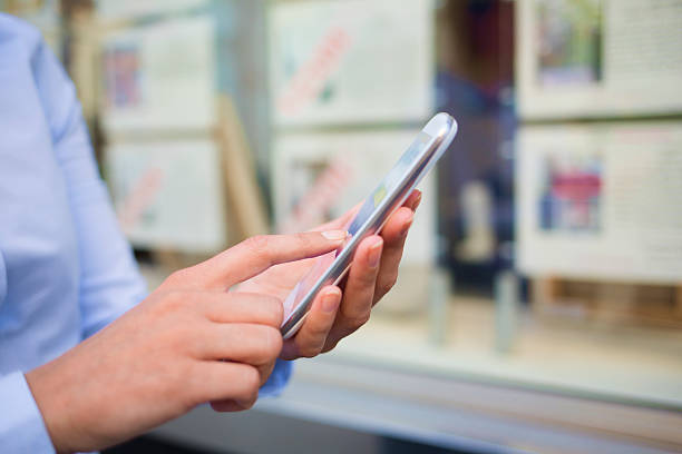 istock Woman using smartphone in front of a real estate office 520281581