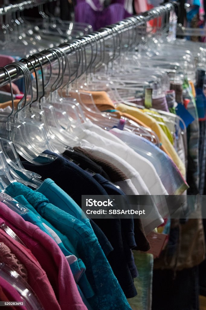Clothing hanging on a rack in a store Colorful children's clothing on clear hangers hanging on a store rack for sale. Arts Culture and Entertainment Stock Photo