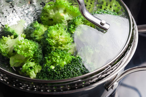 Freshly steamed green broccoli in skimmer pot Freshly steamed green broccoli in skimmer pot preparing vegetables concept steamed photos stock pictures, royalty-free photos & images