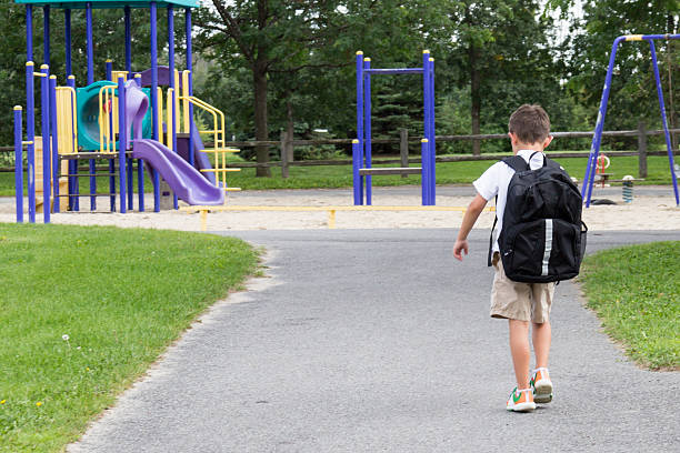 Child with school backpack and book walking in the park stock photo