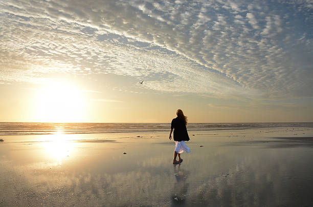 istock Woman walking on the beach at sunrise. 520287292