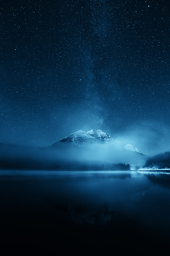 Snow mountain with fog over lake with milky way