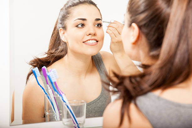 istock Woman plucking her eyebrows with tweezers 520292226
