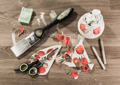 Decoupage accessories laid out on a table. Paintbrush, scissors, pencils, sponge and paper in messy arrangement, Overhead view.